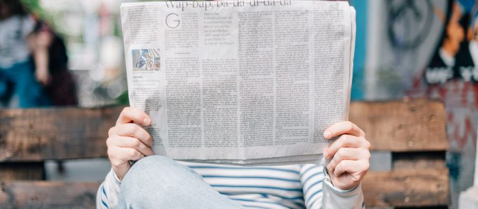 A man sitting on a bench reading a newspaper