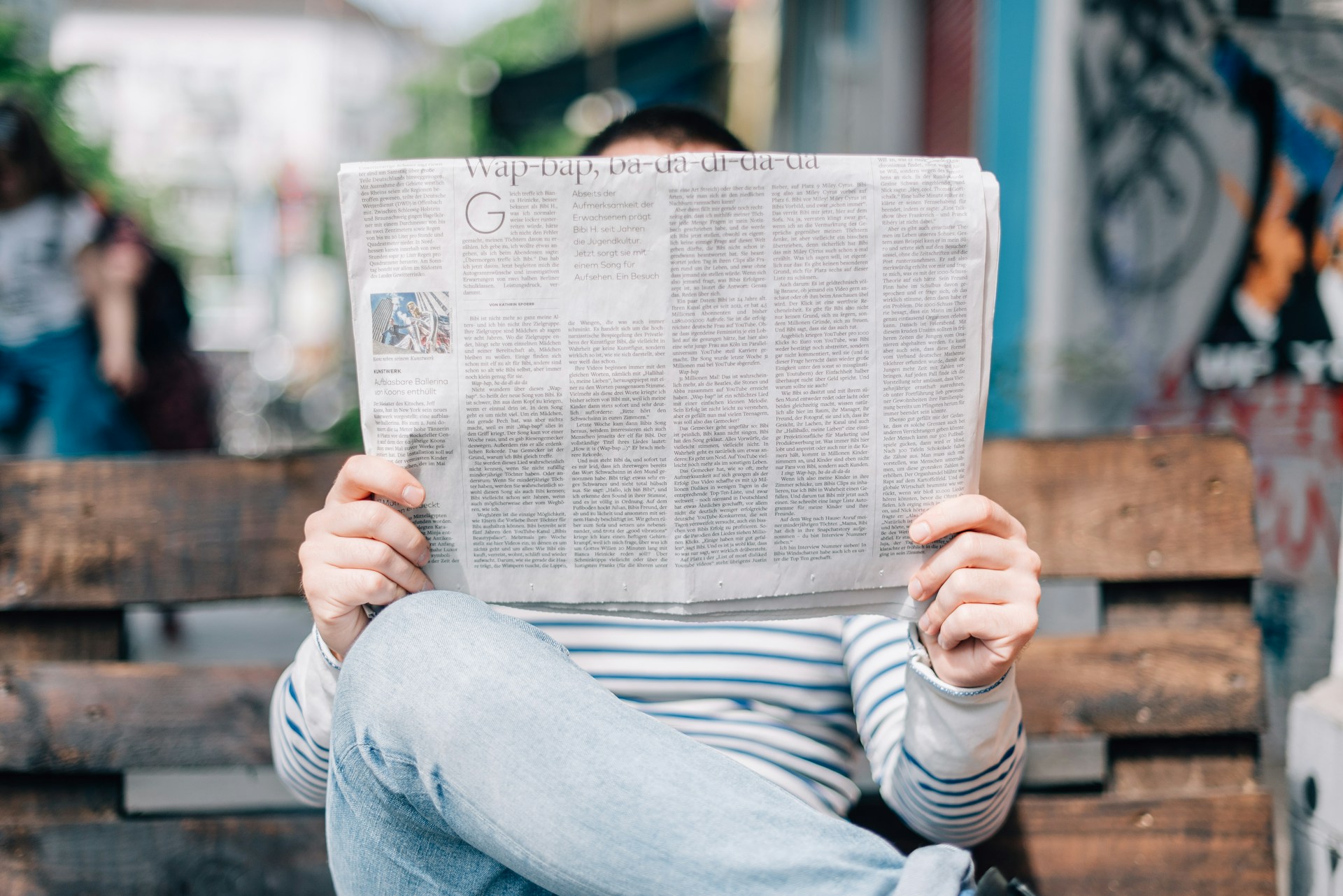 A man sitting on a bench reading a newspaper
