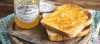 An open jar of marmalade sitting next to two pieces of toast and a butter knife