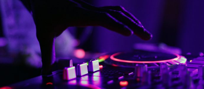 A hand spinning controls on a DJ desk