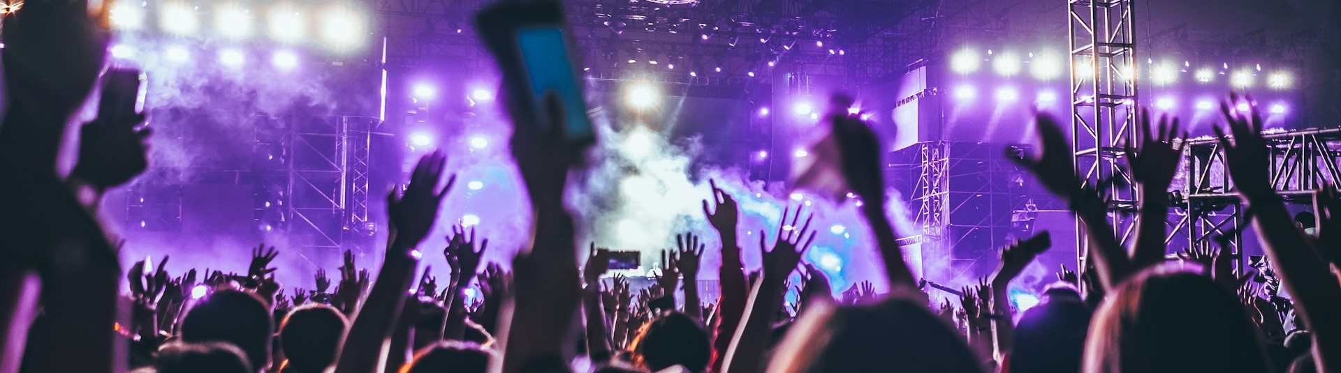 Hands waving at a band on stage at a concert