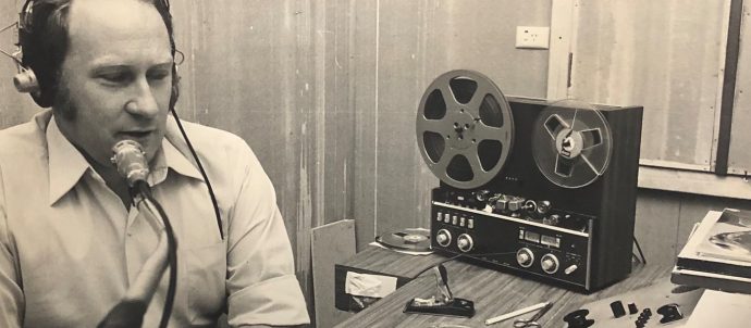 A man next to a reel to reel machine